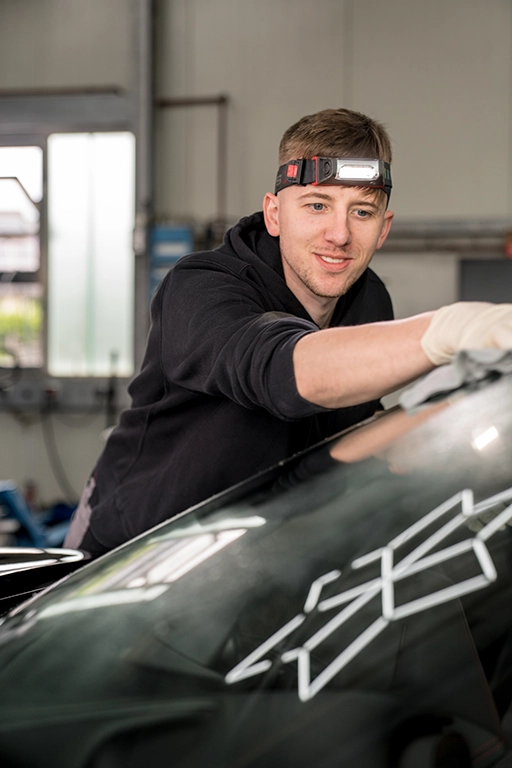 Mitarbeiter von ULTRASCHWARZ bei der professionellen Lackpolitur und Fahrzeugaufbereitung eines schwarzen Fahrzeugs in Bad Berleburg.